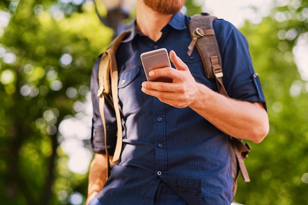 Un uomo tiene uno smartphone d'argento. Avvicinamento.