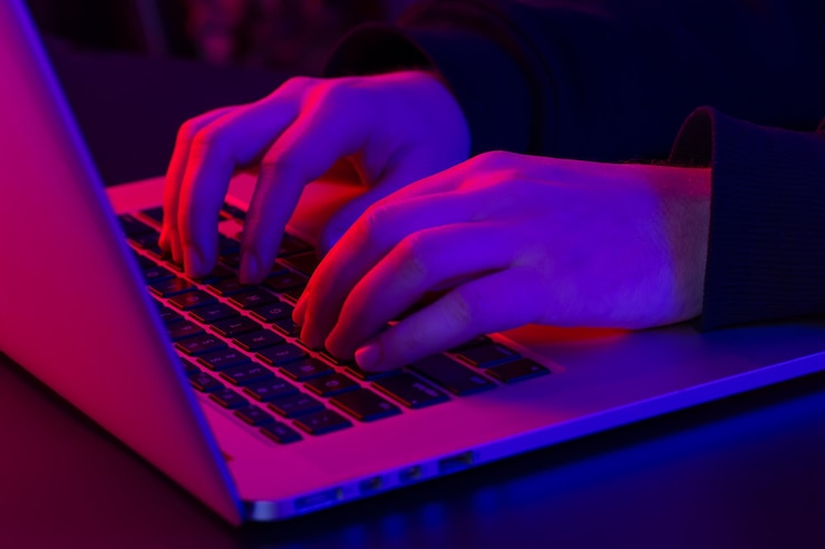 Foto gratuito un uomo usa le mani maschili del primo piano del computer portatile nell'illuminazione al neon