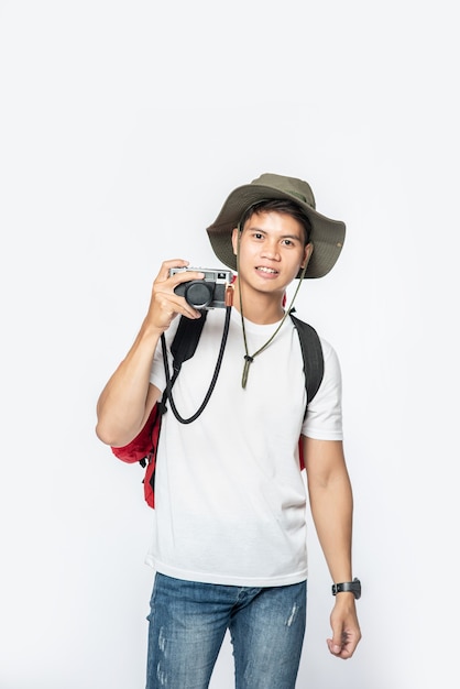 Un uomo vestito per viaggiare con indosso un cappello e prendendo una macchina fotografica