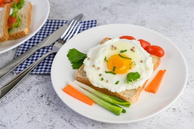 Un uovo fritto, che su un toast, condito con semi di pepe con carote e cipollotti.