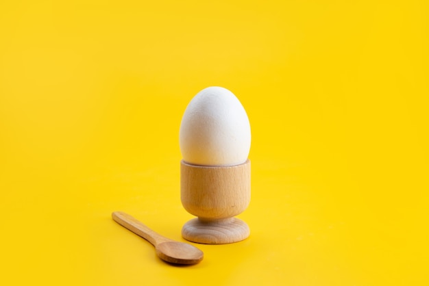 Un uovo sodo di vista frontale all'interno del piccolo supporto sul colore giallo e del pasto dell'alimento