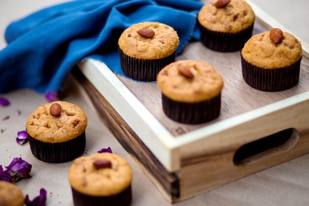 Un vassoio di legno con muffin di base con mandorle in cima