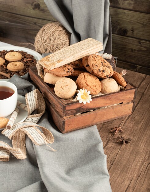 Un vassoio di legno di biscotti e cracker con una tazza di tè