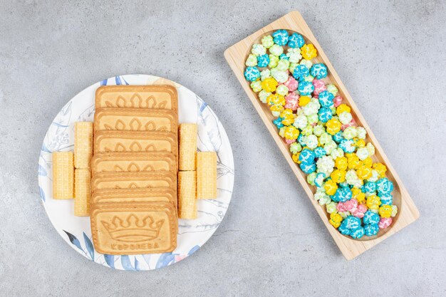 Un vassoio in legno di caramelle popcorn con biscotti allineati su una piastra su sfondo di marmo. Foto di alta qualità