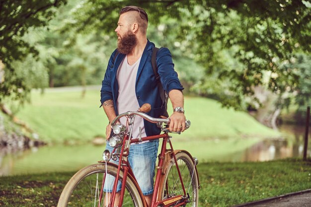 Un viaggiatore vestito con abiti casual con uno zaino, che si rilassa in un parco cittadino dopo aver guidato una bicicletta retrò.