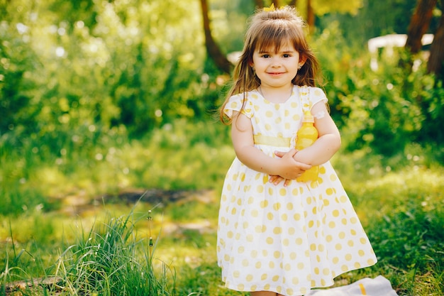 una bambina con i bei capelli lunghi e un vestito giallo sta giocando nel parco estivo