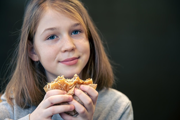 Una bambina con le lentiggini mangia un hamburger