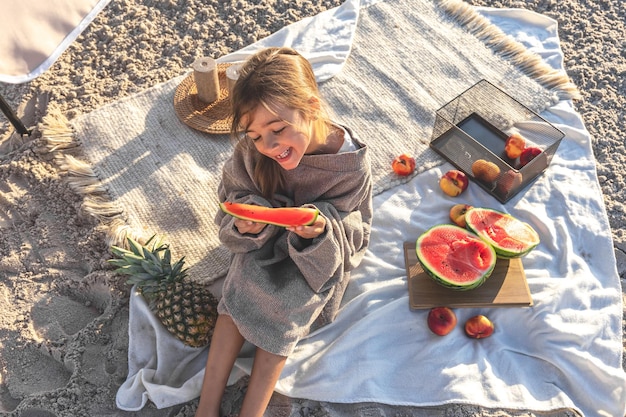 Una bambina su una spiaggia sabbiosa mangia un'anguria