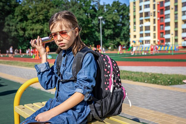 Una bambina, uno studente di scuola elementare con gli occhiali da sole che telefona, parla, comunica.