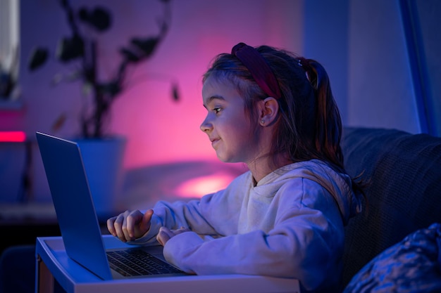 Una bambina usa un laptop a tarda notte