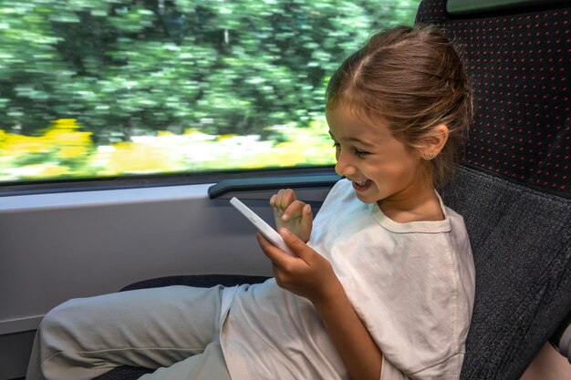 Una bambina usa uno smartphone mentre è seduta su un treno