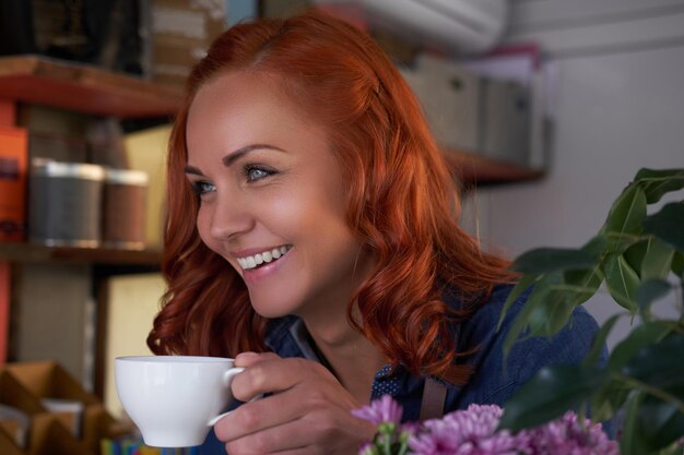 Una barista dai capelli rossi di bellezza beve un caffè, al bar.