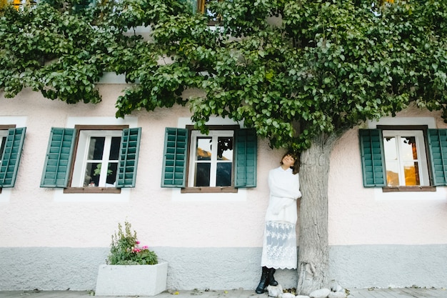 Una bella donna è in piedi vicino all'albero, sorridendo e godendo la vita