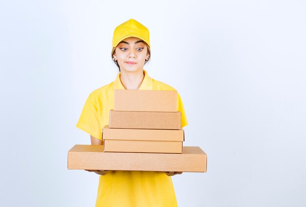 Una bella donna in uniforme gialla che tiene in mano scatole di carta artigianali bianche marroni.