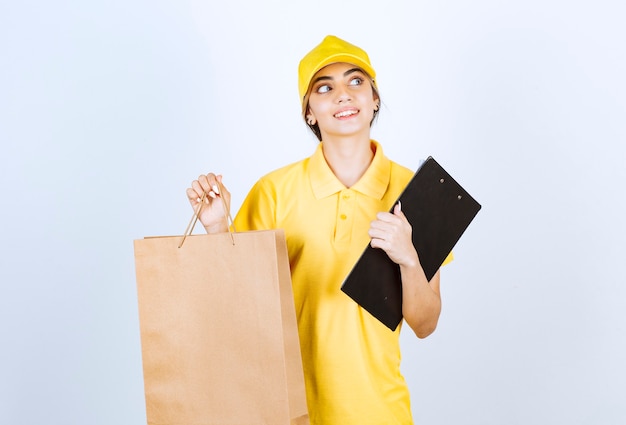 Una bella donna in uniforme gialla che tiene in mano un sacchetto di carta artigianale in bianco marrone.