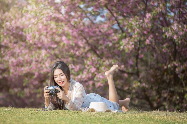 Una bella donna scatta una foto con una cinepresa nel giardino floreale di Sakura.