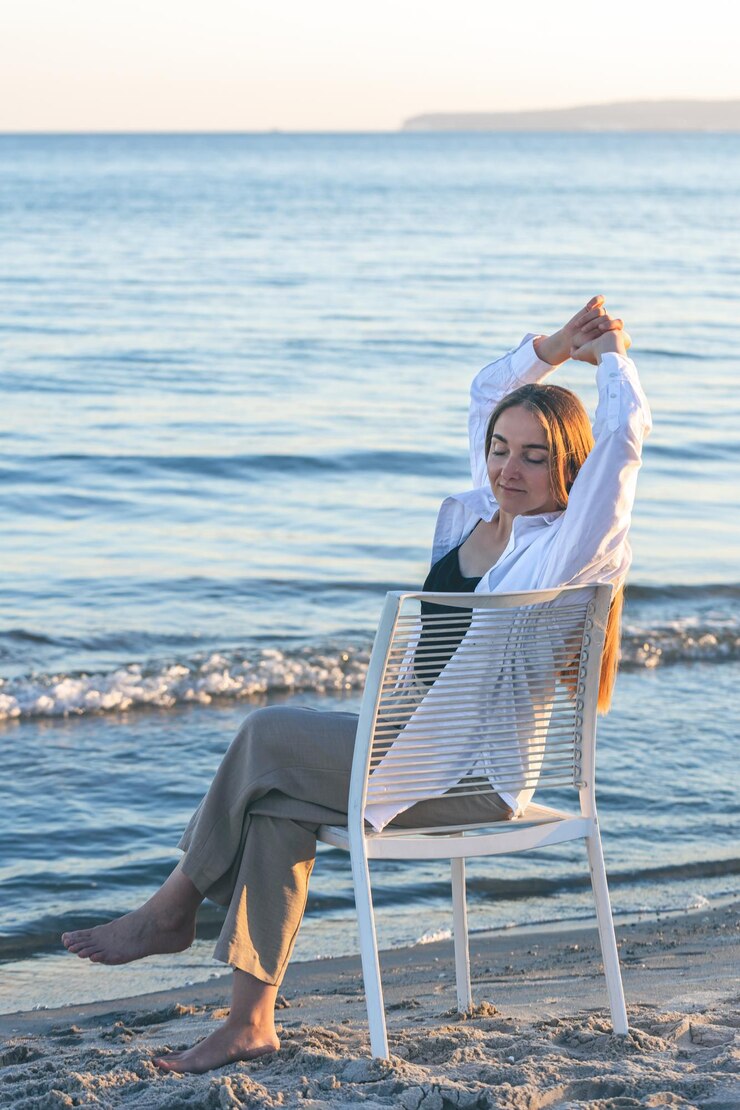 Foto gratuito una bella donna si siede su una sedia vicino al mare