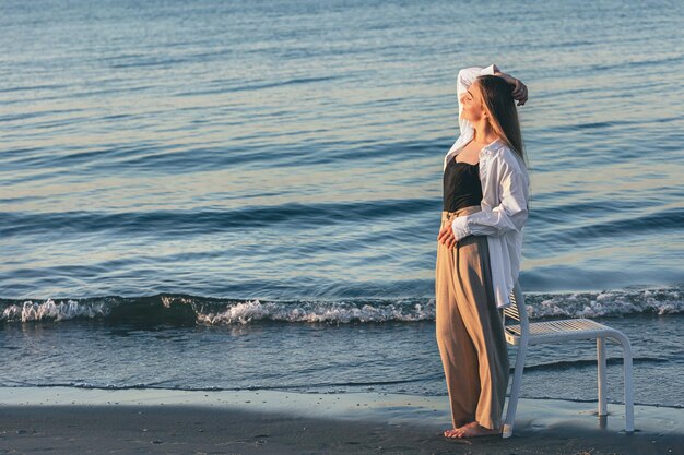 Una bella donna si trova vicino al mare al tramonto