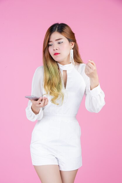 Una bella donna vestita con un abito bianco, mostrando il telefono e le emozioni facciali