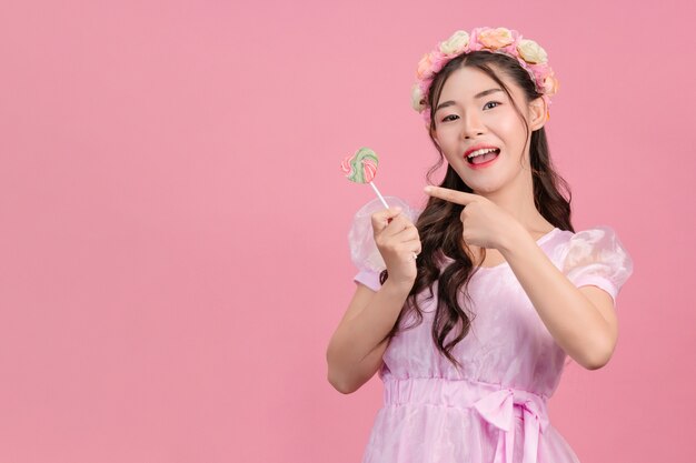 Una bella donna vestita con una principessa rosa sta giocando con le sue dolci caramelle su una rosa.