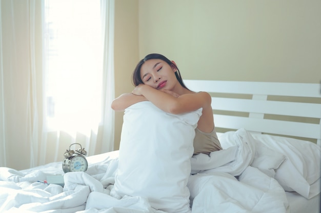 Una bella giovane donna dorme e una sveglia nella camera da letto a casa.