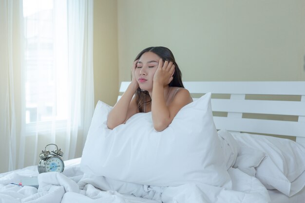 Una bella giovane donna dorme e una sveglia nella camera da letto a casa.