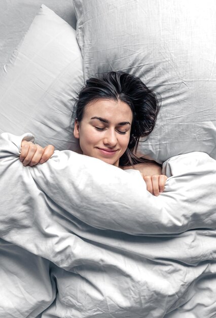 Una bella giovane donna dorme in un letto bianco