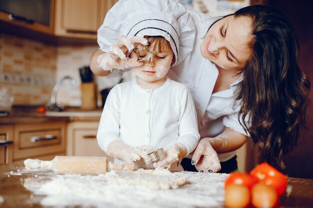 Una bella giovane madre con la sua piccola figlia sta cucinando nella cucina a casa