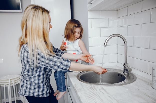 Una bella giovane madre con la sua piccola figlia sta cucinando nella cucina a casa