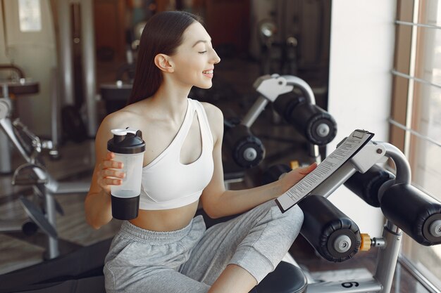 Una bella ragazza seduta con acqua in una palestra