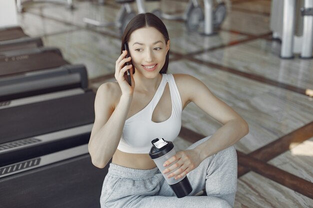 Una bella ragazza seduta con il telefono in una palestra