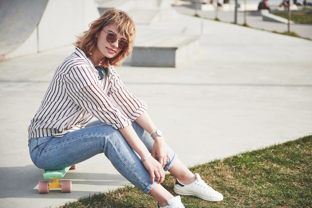 Una bella ragazza si sta divertendo nel parco e in sella a uno skateboard.