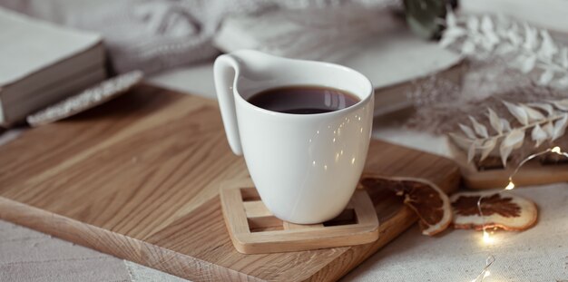 Una bella tazza con tè o caffè su un supporto in legno. Concetto di comfort domestico.