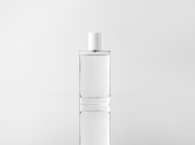 Una bottiglia trasparente vista frontale per le procedure di pulizia del viso sul muro bianco