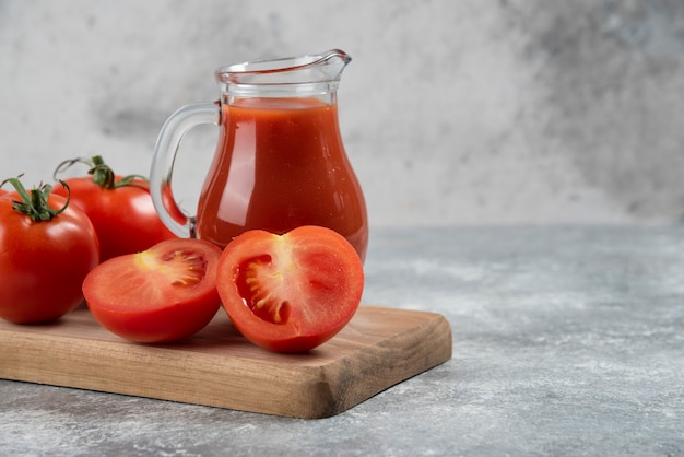 Una brocca di vetro di succo con pomodori freschi.