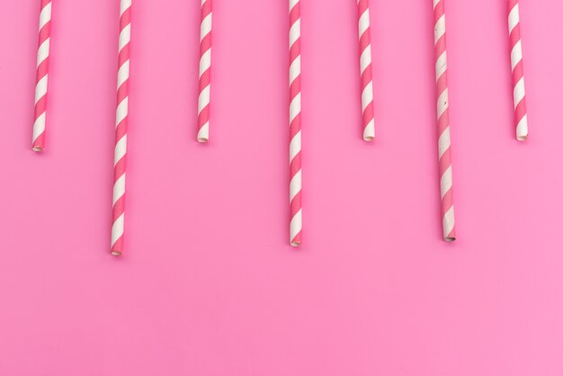 Una caramella rosa-bianca con vista dall'alto attacca deliziosa appiccicosa sul colore rosa, zucchero candito dolci