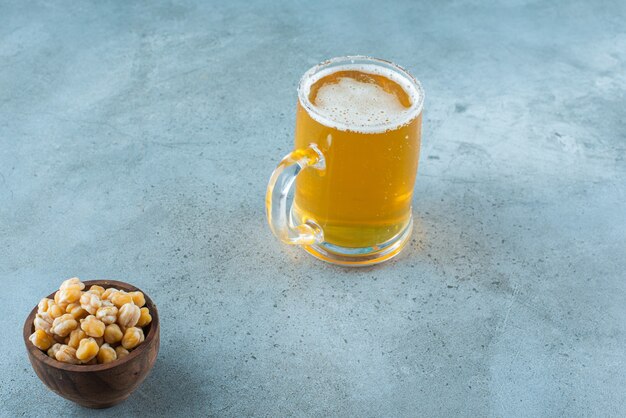 Una ciotola di ceci e un bicchiere di birra, sul tavolo di marmo.