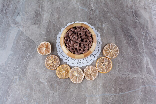 Una ciotola di legno di anelli di cereali al cioccolato con frutta secca a fette