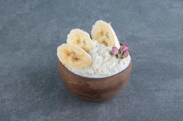 Una ciotola di legno di porridge di farina d'avena con fette di banana.