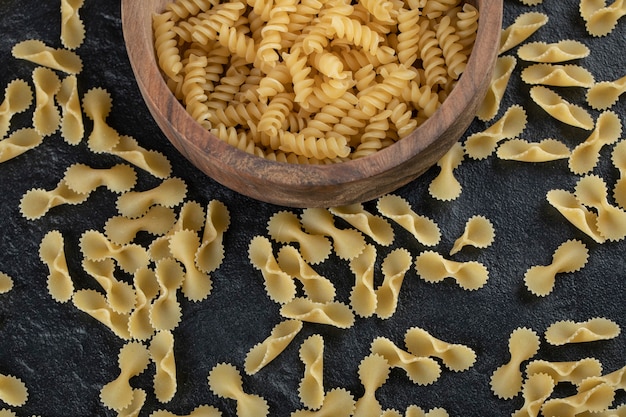 Una ciotola di legno piena di pasta girandole cruda.