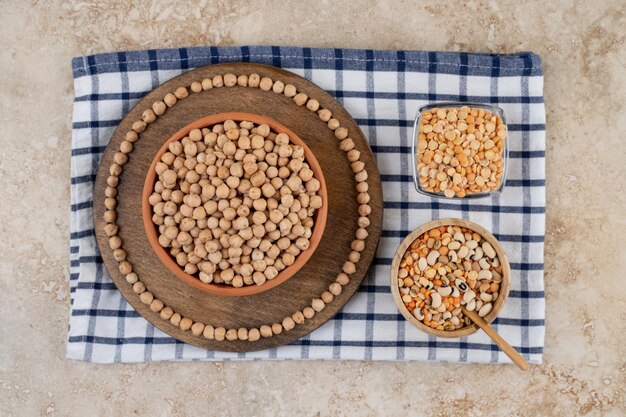 Una ciotola di legno piena di piselli non preparati con spezie e fagioli.