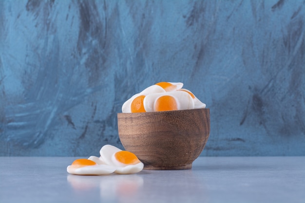 Una ciotola di legno piena di uova fritte in gelatina dolci sul tavolo grigio.