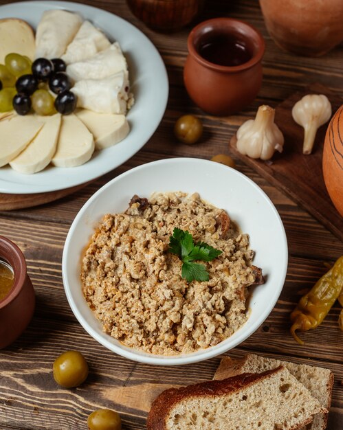 una ciotola di mix di carne macinata con noci tritate servita con piatto di formaggi e pane