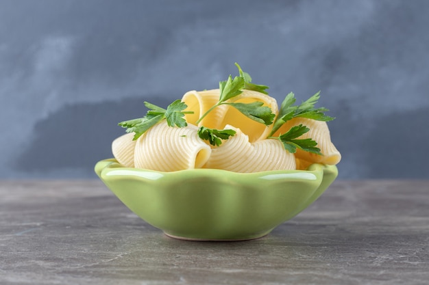 Una ciotola di pasta con verdure, sul marmo.