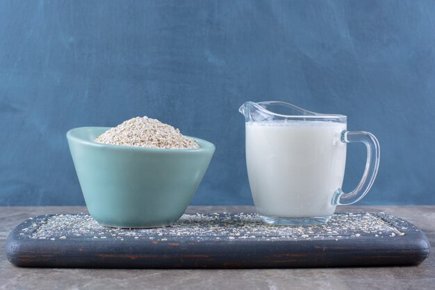 Una ciotola di riso blu con una tazza di latte in vetro su una tavola di legno.