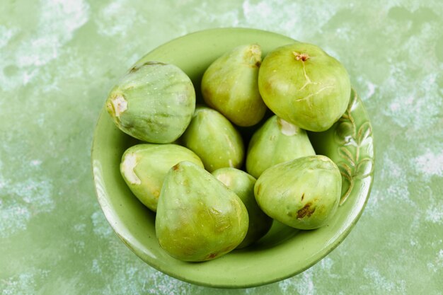 Una ciotola di succosi fichi verdi su verde.