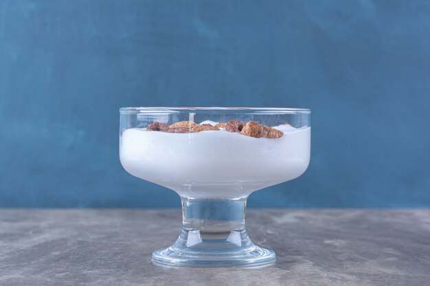 Una ciotola di vetro piena di sano yogurt con deliziosi cereali.