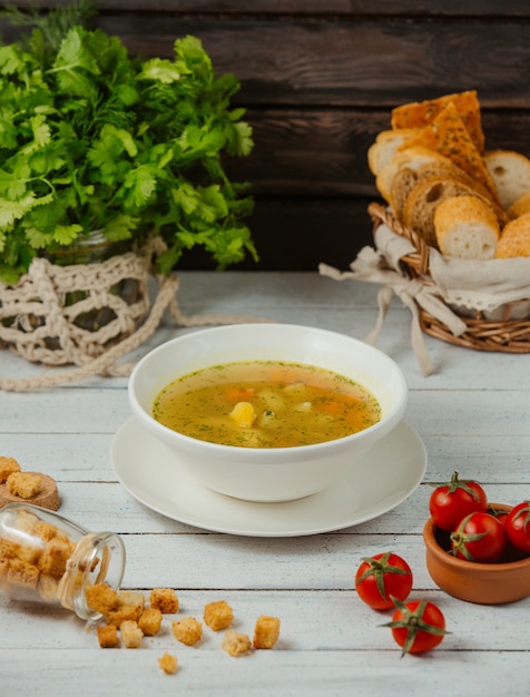 una ciotola di zuppa di pollo con patate, carote e aneto servita con fette di pane