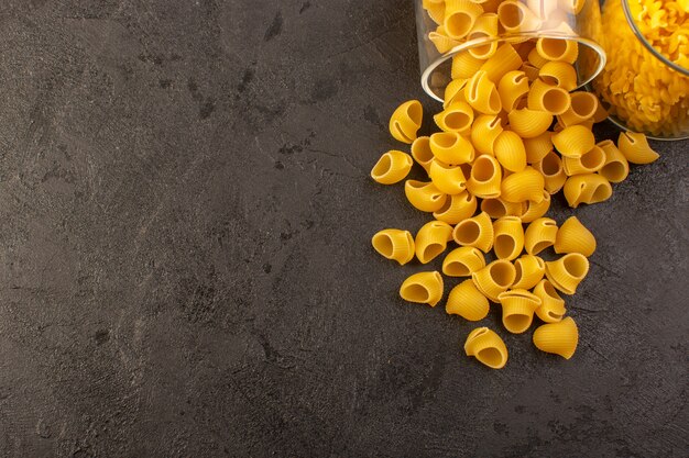 Una ciotola interna cruda di giallo della pasta asciutta italiana di vista frontale isolata sul pasto italiano dell'alimento della pasta del fondo scuro