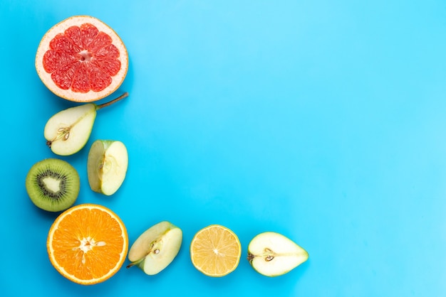 Una composizione di frutta fresca con vista dall'alto affettata dolce e matura su vitamina colore blu, frutta
